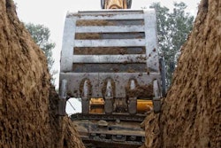 Excavator bucket digging trench stock