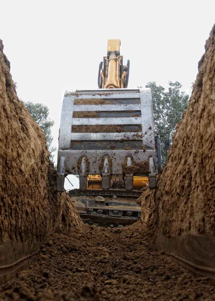 Excavator bucket digging trench stock