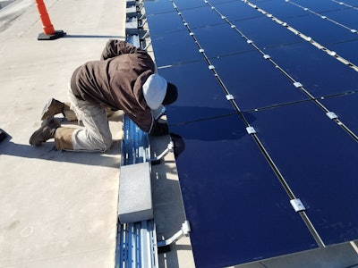 Foley Equipment has gone solar. Show above, a worker installs a solar panel for a Caterpillar microgrid at Foley Equipment.