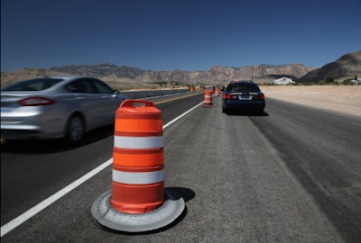 Car passing police car and construction road work cone