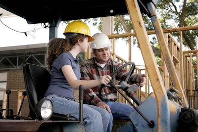 Construction worker teaching a female construction apprentice how to operate heavy equipment