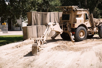 Using the backhoe, the HMEE can locate, excavate and remove improved explosive devices (IEDs). Future versions of the machine will be able to do so without an operator in the cab through the implementation of remote control. Photo: Wayne Grayson