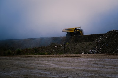 An autonomous haul truck emerges from the fog as it climbs an incline to a dump site.