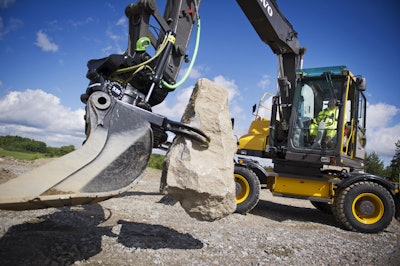 Volvo excavator with tiltrotator grasping a large rock
