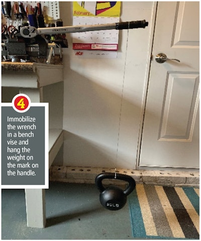 Torque wrench being held in a bench vise with a weight hanging from its handle