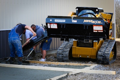 CAT compact track loader with a Danuser Mega Mixer bucket dispensing concrete for workers