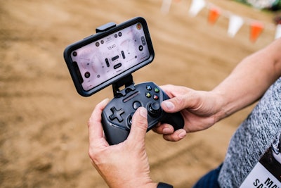 A Steel Series Nimbus video game controller is used in conjunction with the Bobcat MaxControl app running on an iPhone to control a compact track loader.