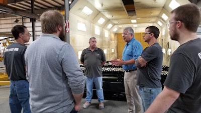 John Lamprinakos (in blue), president and CEO of Screen Machine and Diamond Z, speaks with employees on the factory floor.