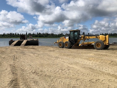 A grader pulls the barge ashore to secure it at a construction site.