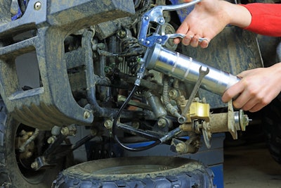 Hand-held grease gun being used to grease equipment parts