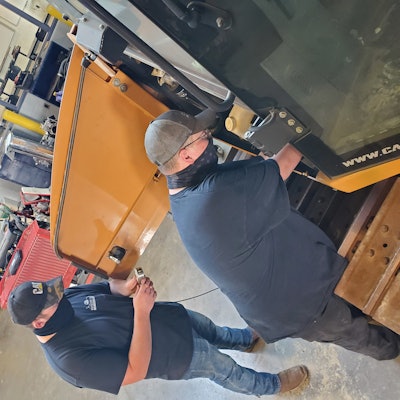 From left, Central Pennsylvania Institute students Drew Albright and Zach Rockey check and reset pump pressures on a dozer.