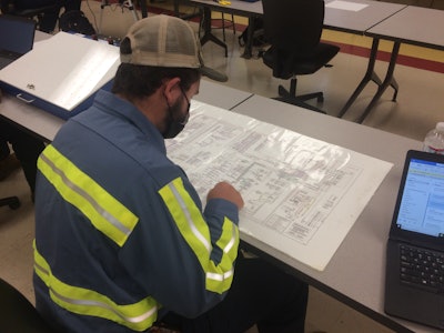 Jorden Gonzales with Carolina Cat traces wires through a schematic drawing at Florence-Darlington Technical Community College.