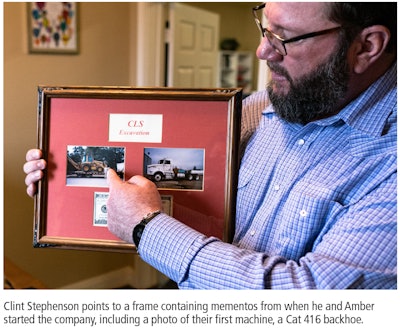 Clint Stephenson pointing to a frame containing photos