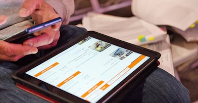 Person holding a smart phone while looking at equipment bids on a tablet