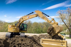 Cat 335 excavator dumping a load of dirt into a dump truck