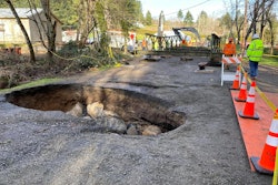 Sinkhole in road with Bailey Bridge assembly in the background