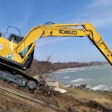 Kobelco SK170LC dumping a bucket of dirt near water