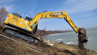 Kobelco SK170LC dumping a bucket of dirt near water