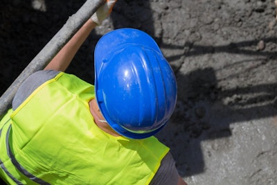 construction worker wearing hard hat and safety vest inside trench