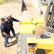 Two men inspecting a piece of John Deere construction equipment
