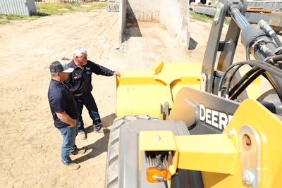 Two men inspecting a piece of John Deere construction equipment