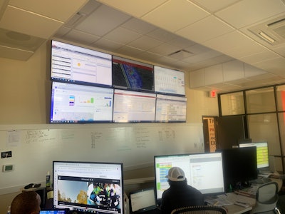 work room with monitors and people at desks on computers