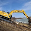 Kobelco excavator dumping dirt next to water