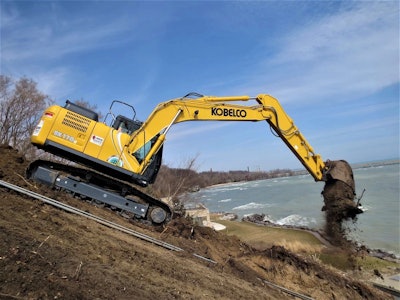 Kobelco excavator dumping dirt next to water