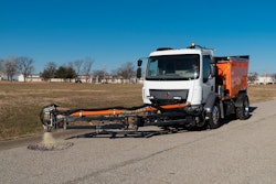 person driving truck with pothole patcher in the process of patching a pothole