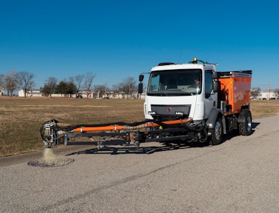 person driving truck with pothole patcher in the process of patching a pothole