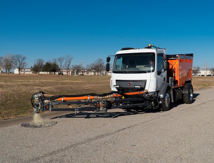 person driving truck with pothole patcher in the process of patching a pothole