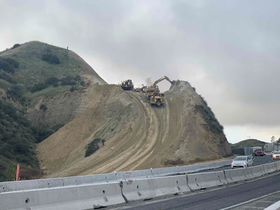 Excavators clearing terrain on side of highway