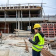 Construction worker wearing bright yellow safety vest and helmet on a construction site