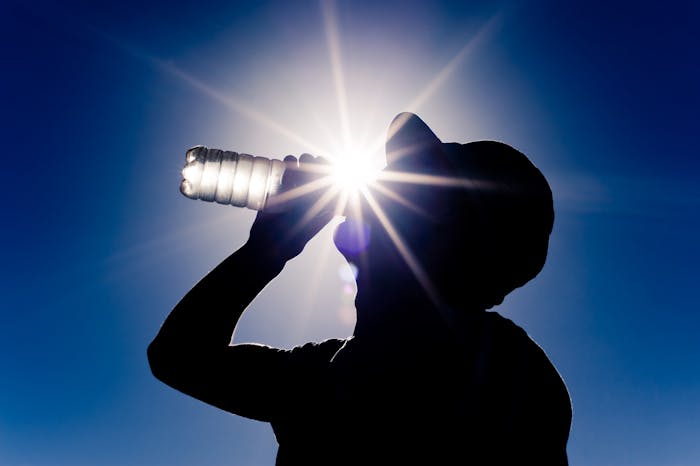 man taking a drink of water from water bottle