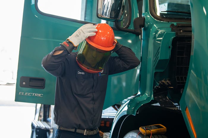 Volvo technician putting on safety helmet with face screen