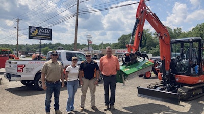 Eric Ransome, Barbara Freund, Matt Valentine, and Mark Laigle standing next to an excavator