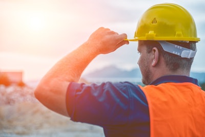 Construction worker wearing a bright orange safety vest and a yellow hardhat