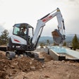 Bobcat E35 compact excavator scooping up dirt on a jobsite