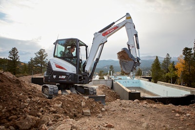 Bobcat E35 compact excavator scooping up dirt on a jobsite