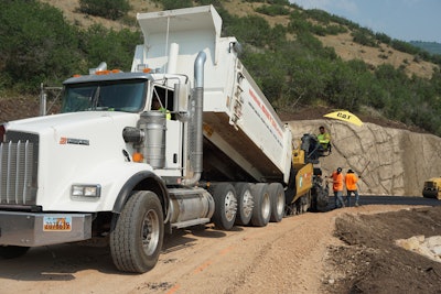 Dump truck pouring asphalt material onto a road