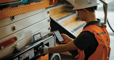 Service technician diagnosing scissor lift issue with mobile app.