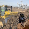 Komatsu bulldozer and a person controlling a Smart Construction Field Drone with a smartphone