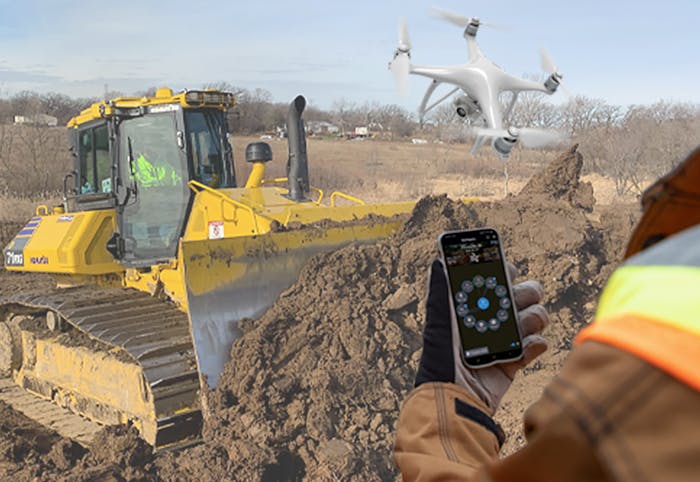 Komatsu bulldozer and a person controlling a Smart Construction Field Drone with a smartphone