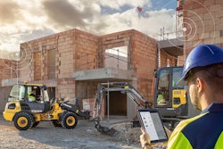 Man looking at tablet on a connected jobsite with Volvo construction equipment.