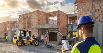 Man looking at tablet on a connected jobsite with Volvo construction equipment.