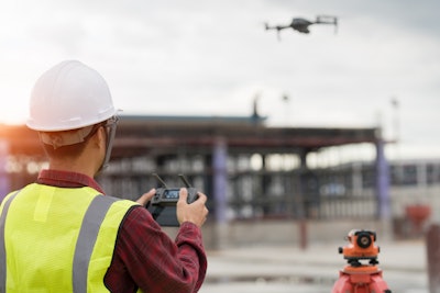 Construction worker flying a drone at a jobsite.