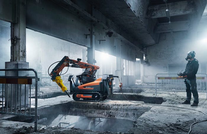 Construction worker uses a Husqvarna demolition robot inside a building.