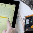 Man checks a Volvo excavator's loading efficiency on a tablet.