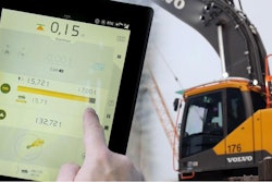 Man checks a Volvo excavator's loading efficiency on a tablet.