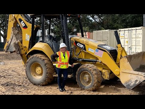 woman contractor standing next to cat 420f2 equipment